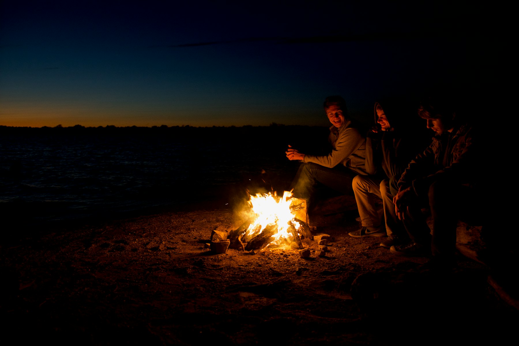 A family gathered around a beach fire after dark