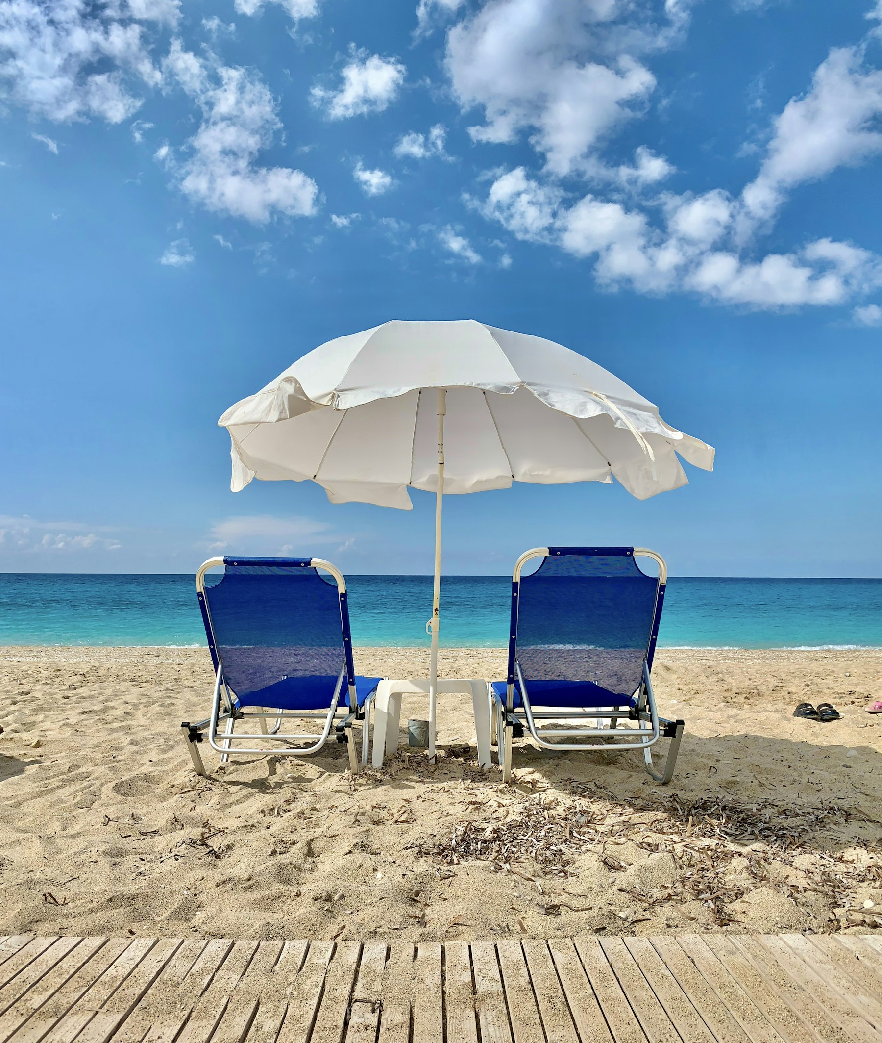 A shaded beach canopy with chairs set up by the surf