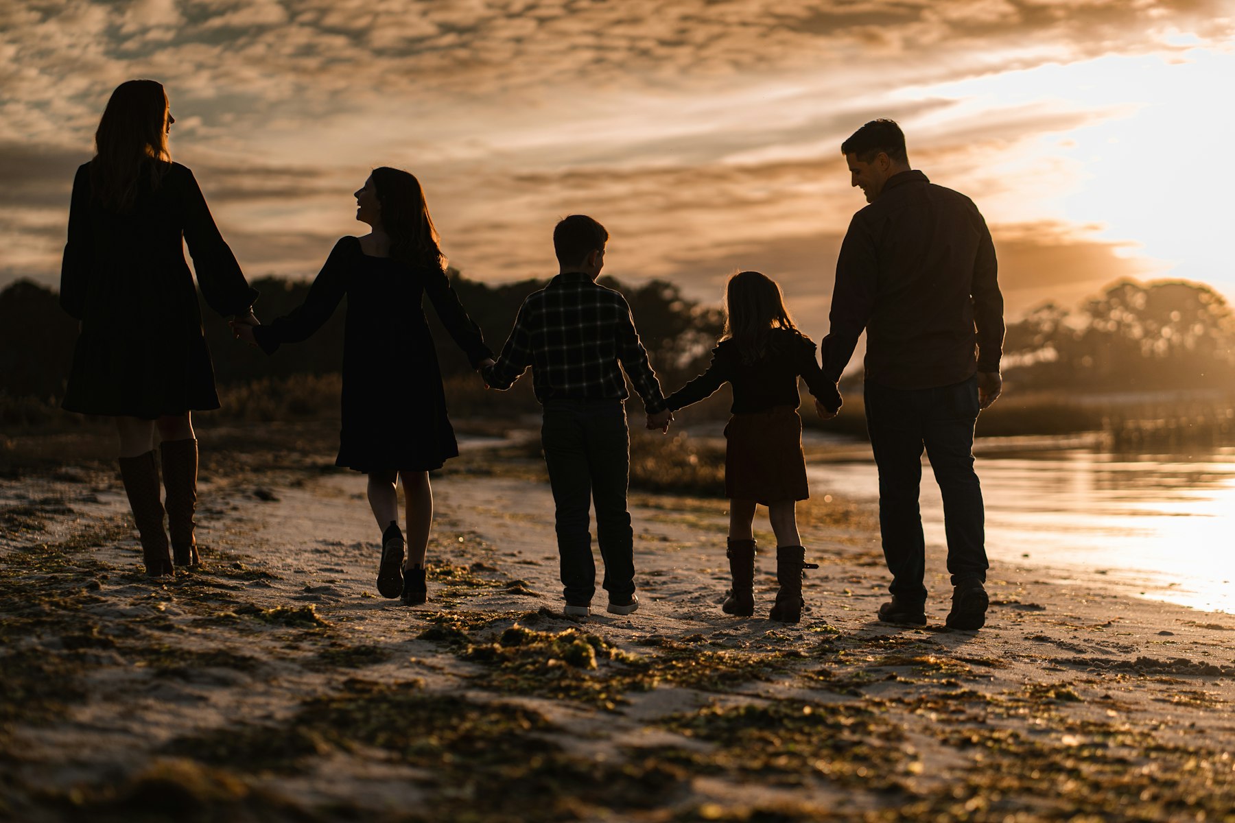A family of five walking the shoreline at golden hour